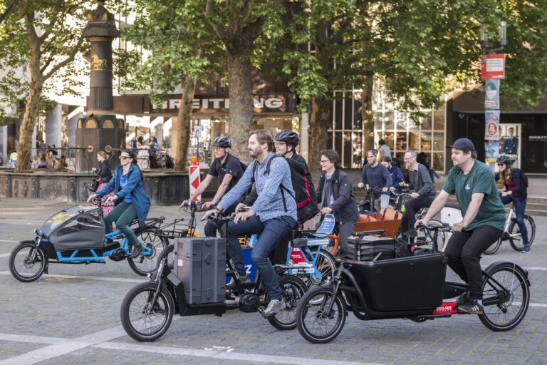 Mehrere Menschen fahren mit dem Lastenrad durch die Stadt