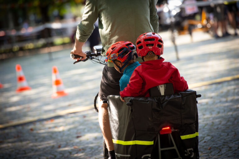 Mann mit zwei Kindern auf einem E-Lastenrad von hinten fotografiert