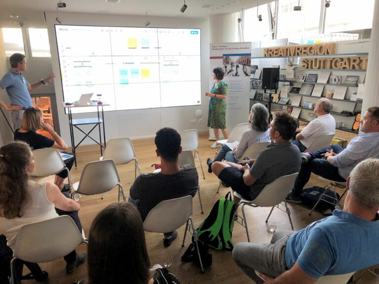 Seminarteilnehmer und zwei Personen präsentieren vor einer Leinwand